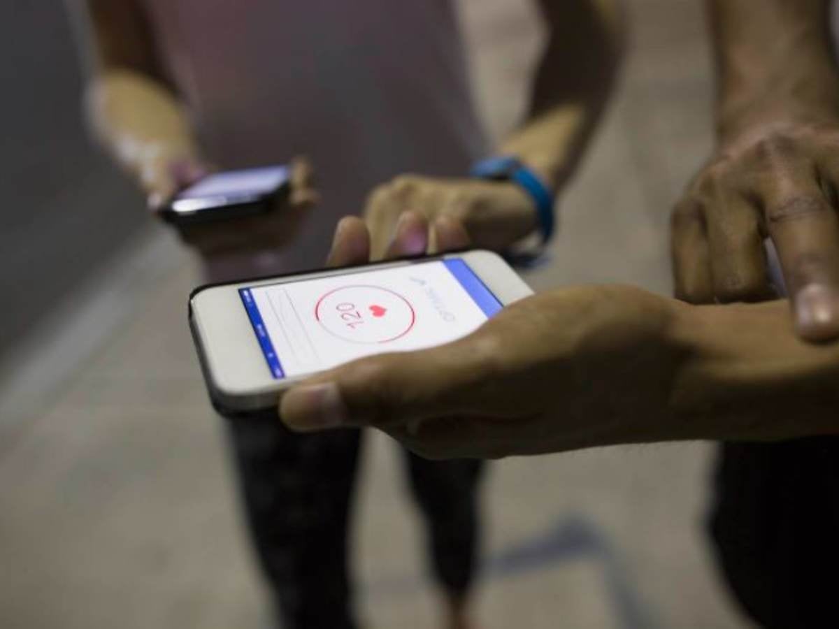 Two people taking their pulse while viewing a pulse monitor on their smartphones